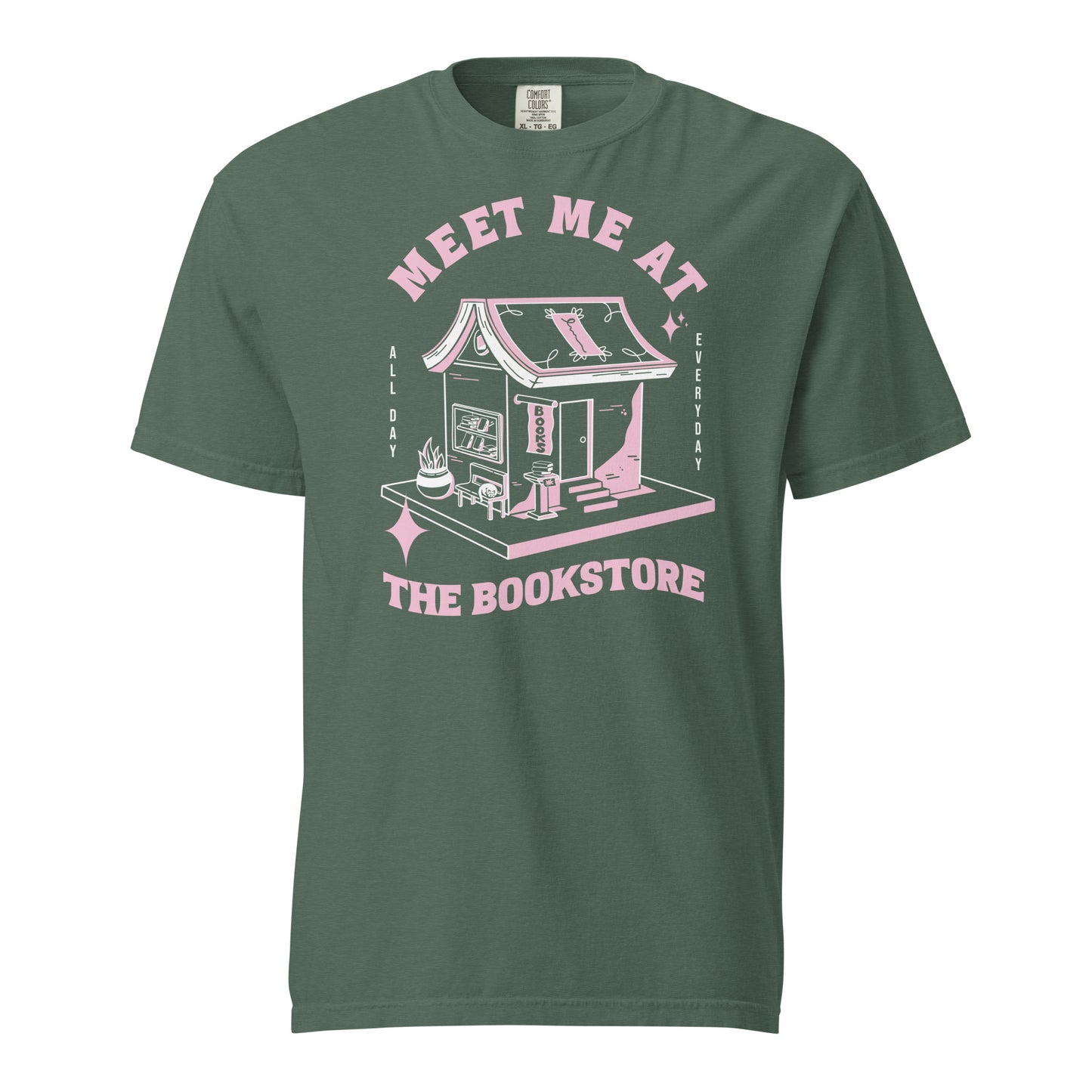 Blue Spruce Comfort Colors t-shirt with a hand-drawn design of a bookstore with a cute cat on a bench and books in the window, and an open book as a roof, with the text "Meet me at the Bookstore", Vertical text on either side reads all day, and everyday.