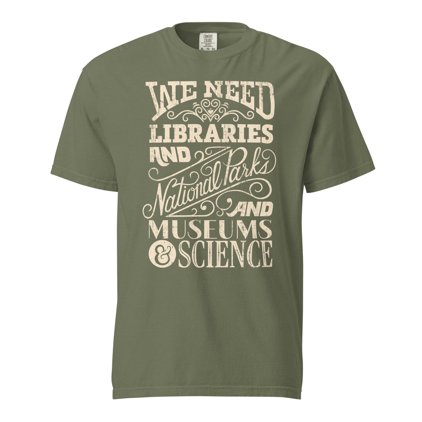 Moss Green Comfort Colors t-shirt with a hand lettered typography design reading "We Need Libraries and National Parks and Museums and Science."