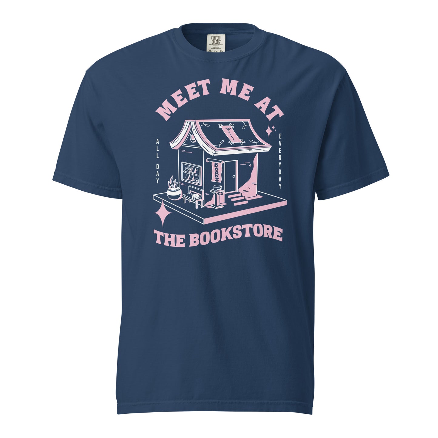 True Navy Comfort Colors t-shirt with a hand-drawn design of a bookstore with a cute cat on a bench and books in the window, and an open book as a roof, with the text "Meet me at the Bookstore", Vertical text on either side reads all day, and everyday.