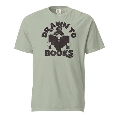 Bay Tan Gray t-shirt with Drawn to Books logo, text says "Drawn to Books" which is framed around a girl reading a book, and you can see only the top of her ponytail, hands and feet, and the big book she's reading.