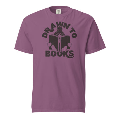 Berry Purple Pink Red t-shirt with Drawn to Books logo, text says "Drawn to Books" which is framed around a girl reading a book, and you can see only the top of her ponytail, hands and feet, and the big book she's reading.