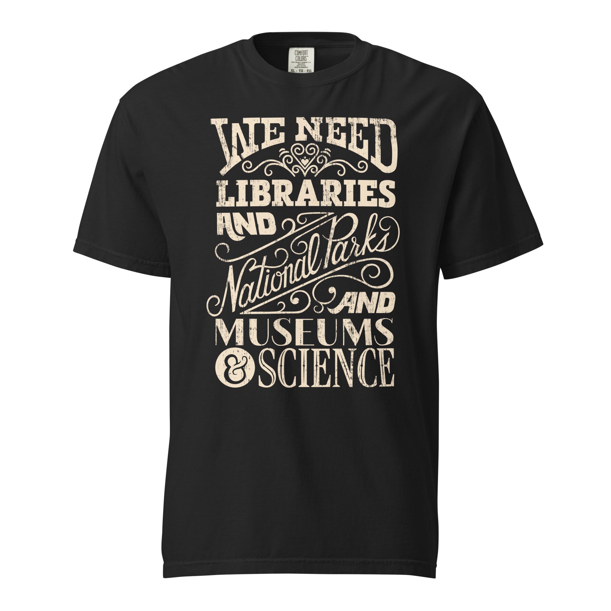 Black Comfort Colors t-shirt with a hand lettered typography design reading "We Need Libraries and National Parks and Museums and Science."