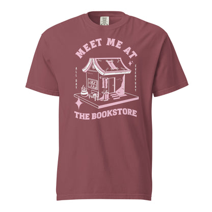 Brick Comfort Colors t-shirt with a hand-drawn design of a bookstore with a cute cat on a bench and books in the window, and an open book as a roof, with the text "Meet me at the Bookstore", Vertical text on either side reads all day, and everyday.