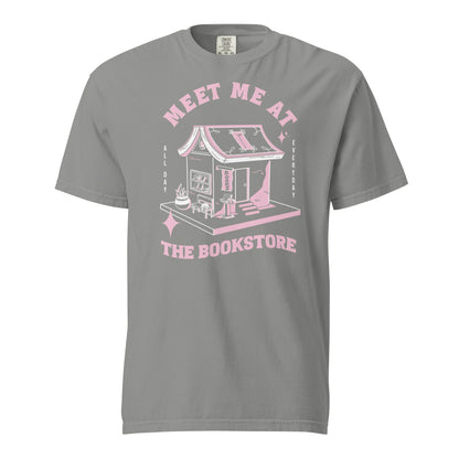 Gray Comfort Colors t-shirt with a hand-drawn design of a bookstore with a cute cat on a bench and books in the window, and an open book as a roof, with the text "Meet me at the Bookstore", Vertical text on either side reads all day, and everyday.
