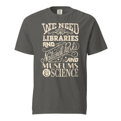 Pepper Gray Comfort Colors t-shirt with a hand lettered typography design reading "We Need Libraries and National Parks and Museums and Science."