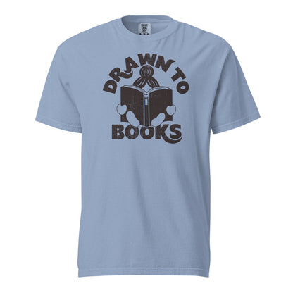 Washed Denim Blue Gray t-shirt with Drawn to Books logo, text says "Drawn to Books" which is framed around a girl reading a book, and you can see only the top of her ponytail, hands and feet, and the big book she's reading.